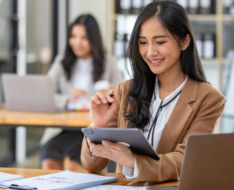 Asian businesswomen work using laptops and tablets, calculators to calculate make an account analysis report real estate investment information financial system concept and tax.